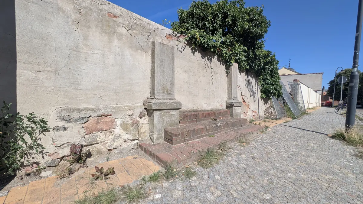 Die denkmalgeschützte Mauer der Berliner Straße 18 in Altlandsberg. Anstatt des Parkplatzes, der dahinter entstehen sollte, muss jetzt die Stadt mit dem Geld die marode Mauer sanieren. Der Parkplatz liegt erst einmal auf Eis.