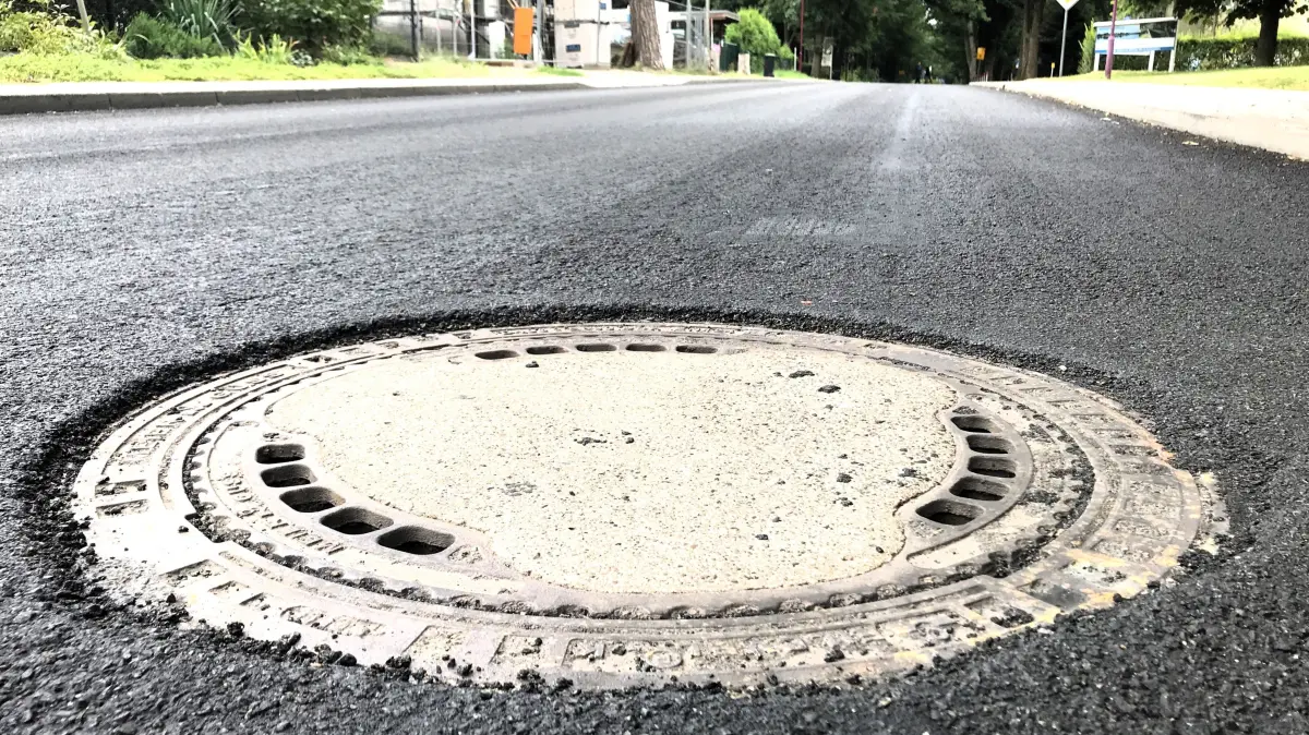 Müllrose. Mixdorfer Straße. Nach dem Aufbringen einer neuen dünnen Asphaltdeckschicht ist der Asphalt auf der Fahrbahn bis zu 3 cm höher als die Gullys und die Schachtabdeckungen. Gefährlich kann das vor allem für Zweiradfahrer sein. 21.08.2026 Foto: Frank Groneberg