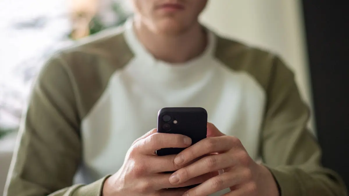 Ein junger Mann tippt auf seinem Handy