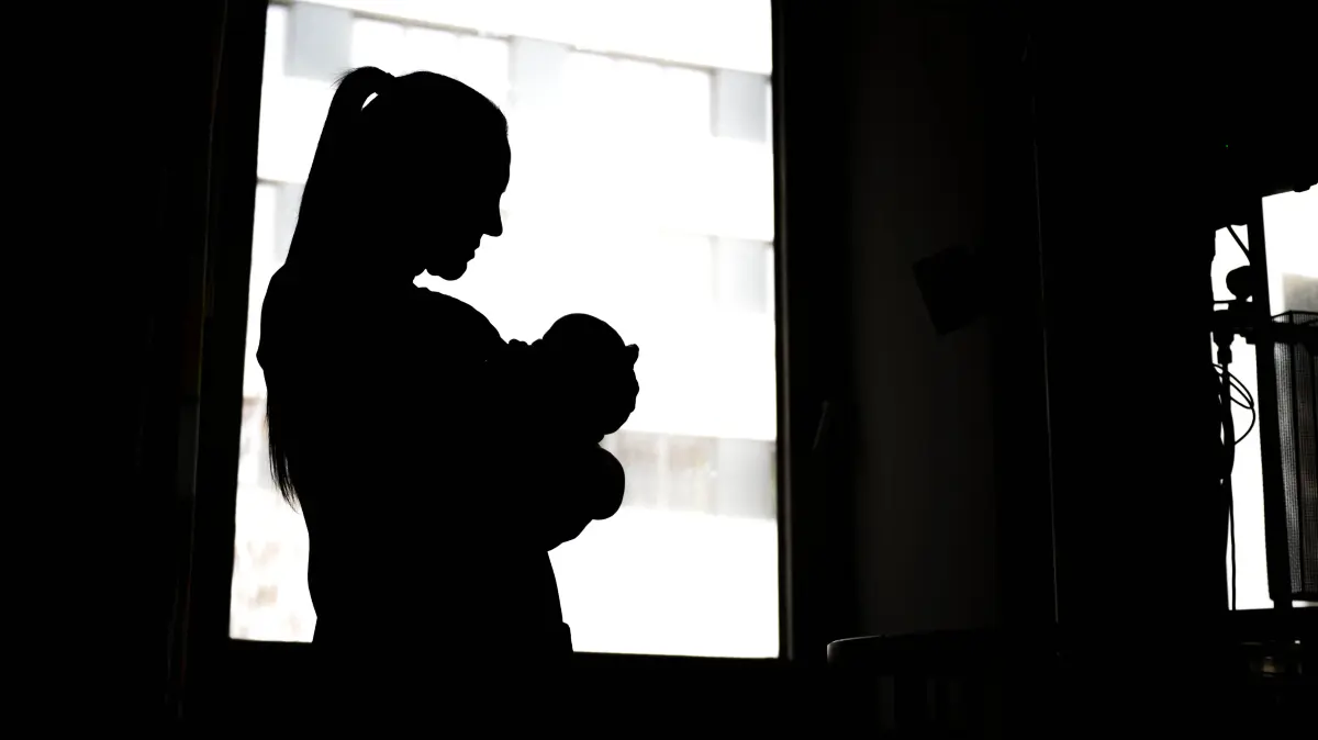 Eine Frau steht mit einem Neugeborenen am Fenster einer Klinik. Nachdem in Brandenburg die letzte Babyklappe geschlossen hat, stellt sich die Frage, wie Frauen in Not geholfen werden kann. Es gibt eine vielfach bevorzugte Variante. (Symolbild)