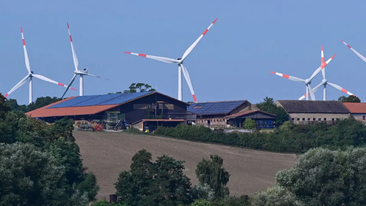 Windenergie in Brandenburg: 26.08.2026, Brandenburg, Libbenichen: Windenergieanlagen ragen über die Dächer eines Bauernhofs im östlichen Brandenburg. Brandenburg ist nach Niedersachsen und Schleswig-Holstein das drittstärkste Windenergieland in Deutschland. Laut dem Marktstammdatenregister (MaStR) mit Stand vom Januar 2026 sind im Land Brandenburg 4.150 Windenergieanlagen (WEA) mit einer Gesamtleistung von rund 9.550 MW installiert. Foto: Patrick Pleul/dpa +++ dpa-Bildfunk +++