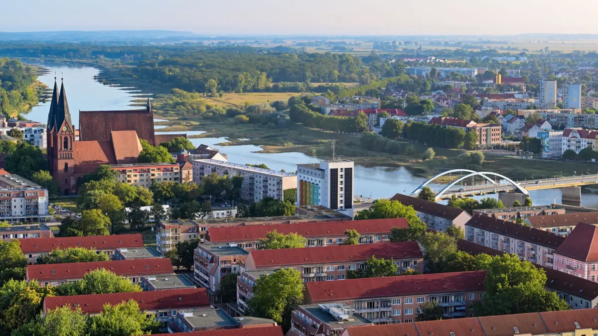 Morgenstimmung in Brandenburg: 27.08.2026, Brandenburg, Frankfurt (Oder): Blick am frühen Morgen aus einem Hochhaus über die Dächer der Stadt Frankfurt (Oder) mit der Friedenskirche (l), sowie dem deutsch-polnischen Grenzfluss Oder. Nach freundlichem Wetter drohen laut DWD im Wochenverlauf kräftige Schauer und Gewitter in der Region. Foto: Patrick Pleul/dpa - Honorarfrei nur für Bezieher des Dienstes ZB-Funkregio Ost +++ ZB-FUNKREGIO OST +++