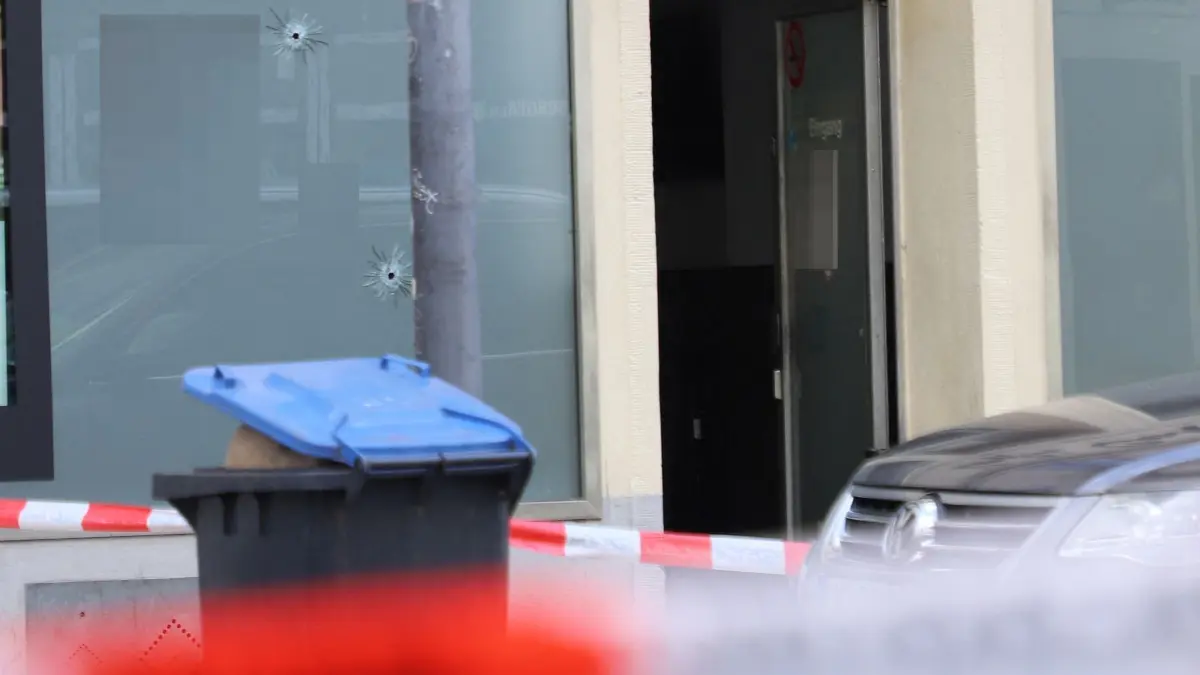 Schüsse auf Café in Kölner Südstadt: 31.08.2026, Nordrhein-Westfalen, Köln: Einschusslöcher sind hinter einer Absperrung an der Fensterscheibe eines Cafés zu sehen. Schüsse auf ein Café in der Kölner Südstadt haben am Morgen für einen Großeinsatz der Polizei gesorgt - die Einsatzkräfte fahnden nach einem Täter. Verletzte oder Tote gibt es laut Polizeiangaben nicht. Foto: ---/dpa +++ dpa-Bildfunk +++