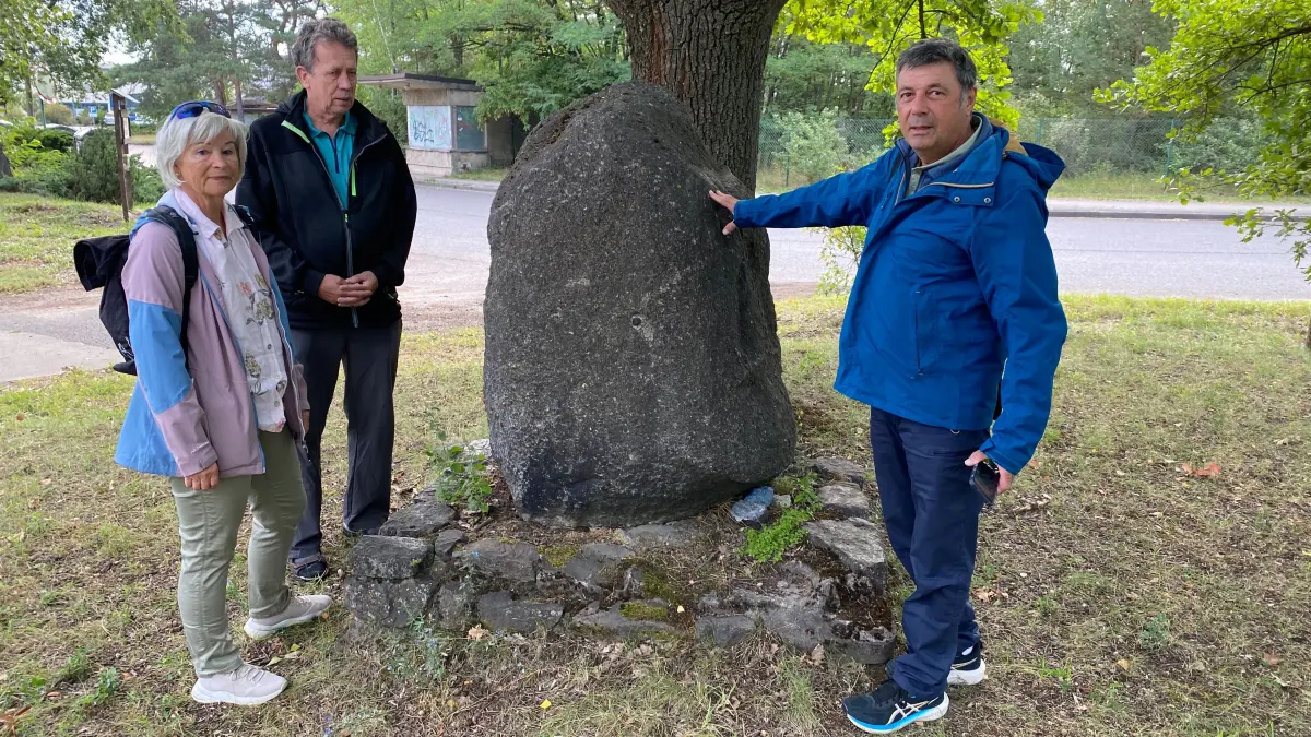 Untersuchen den Gedenkstein neben der Eiche nach einer verwischten Inschrift: Petra Mai, Erich Opitz und Michel Crochat (von links). Gedenkstein und Eiche vor dem Lagereingang stammen wahrscheinlich aus dem Sommer 1943.