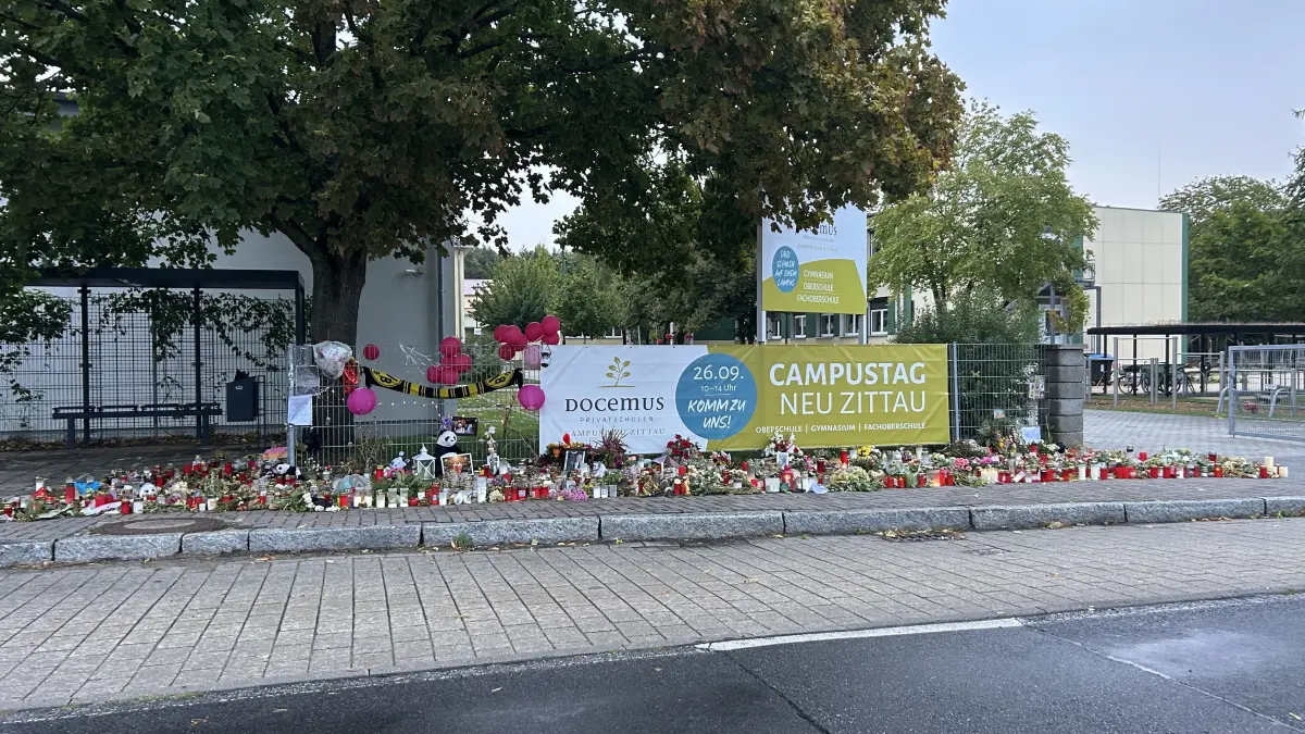 Vor der Schule in Gosen-Neu Zittau haben unzählige Menschen Blumen und Kerzen in Gedenken an die Verstorbenen niedergelegt. Auch persönliche Botschaften finden sich darunter.