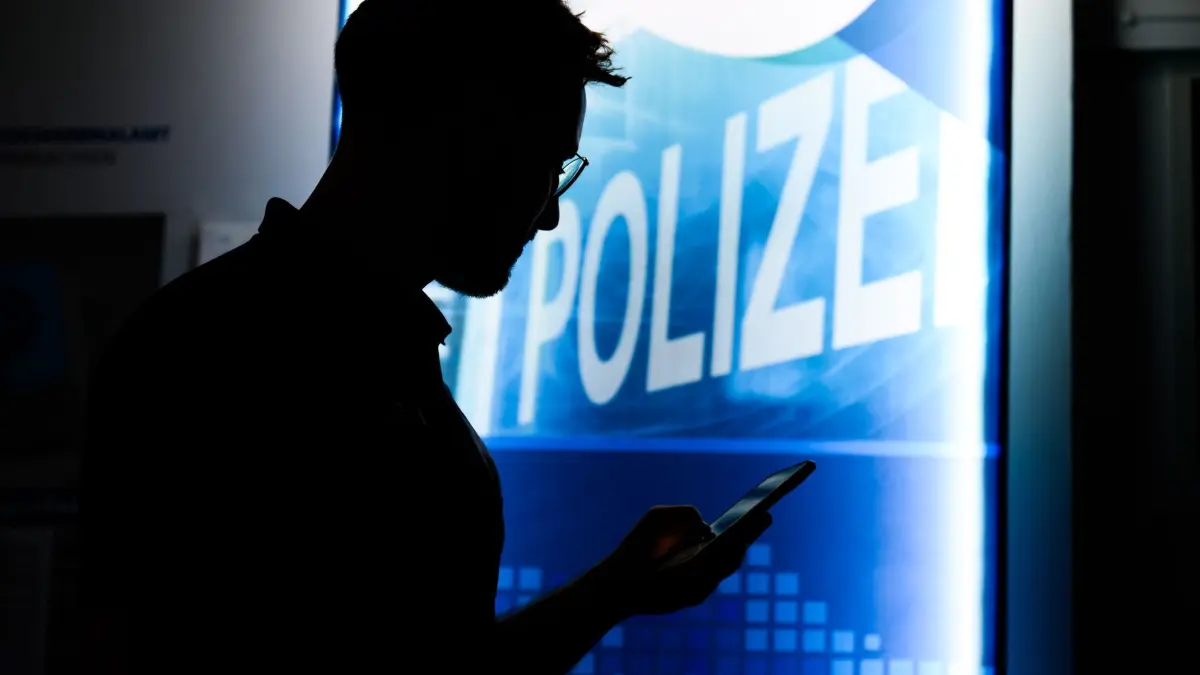 Cyberkriminalität: ARCHIV - 30.04.2024, Niedersachsen, Hannover: Ein Polizist steht mit einem Smartphone in der Präventionsstelle Cyberkriminalität im Landeskriminalamt Niedersachsen (gestellte Szene). (zu dpa: «Hackerangriff könnte größere Folgen haben als bisher gedacht») Foto: Julian Stratenschulte/dpa +++ dpa-Bildfunk +++