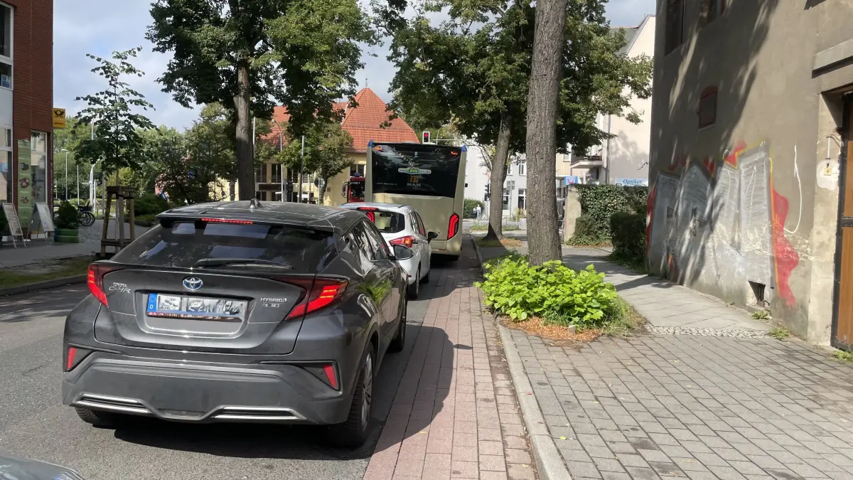Autos und Busse stehen an der Kreuzung Eichenallee/Cottbusser Straße/Luckenwalder Straße/Schloßstraße auf dem Radweg, während sie auf die grüne Ampel warten.