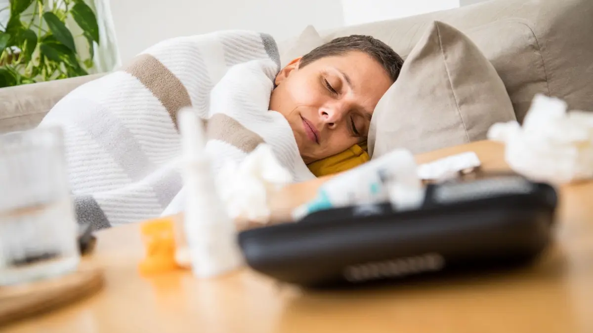 Eine Frau liegt krank auf einem Sofa: ILLUSTRATION - Schmerzmittel und Nasenspray lindern Symptome einer Erkältung - schneller gesund wird man dadurch aber in der Regel nicht. (zu dpa: «Vitamin C? Warmes Bier? 8 Erkältungstipps im Check») Foto: Christin Klose/dpa-tmn - Honorarfrei nur für Bezieher des dpa-Themendienstes +++ dpa-Themendienst +++