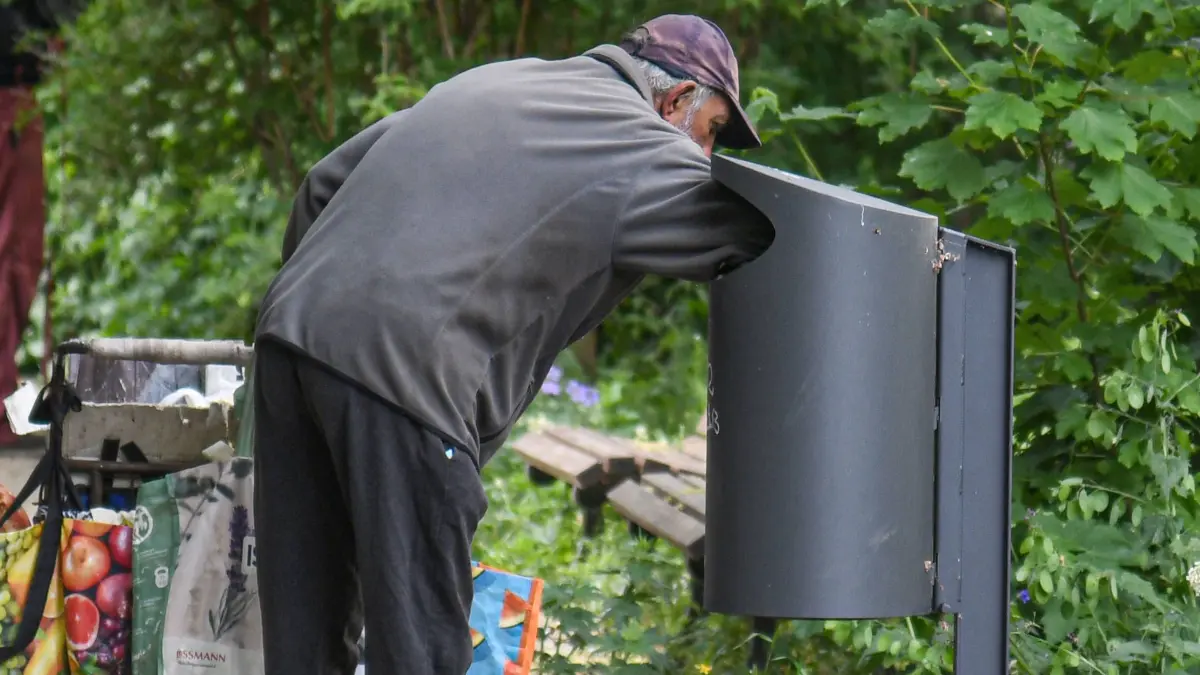 Abfalleimer, Arm, Armut, Berlin, Flaschensammler, : Ein aelterer Mann durchsucht einen Abfalleimer in einem Park in Berlin-Friedrichshain nach leeren Flaschen. *** An elderly man searches a garbage can in a park in Berlin Friedrichshain for empty bottles