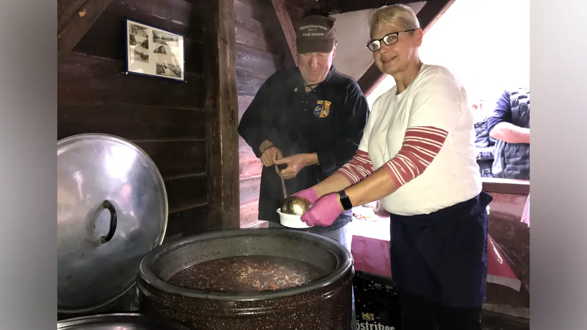 Groß Lindow. 17. Köhlerfest des Kienstubbenvereins am 03.10.2026. Im Bild: Simone Rieckmann und Gerhard Siewert schenken die selbst gekochte Schlaubetaler Köhlersuppe aus dem Kessel aus. Insgesamt 180 Liter Suppe haben sie gekocht. Foto: Frank Groneberg