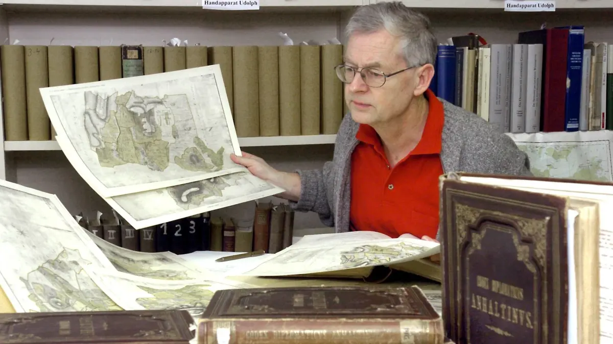 Deutschlands einziger Professor für Namenkunde (Onomastik), Jürgen Udolph, erforscht an der Universität in Leipzig mit Hilfe von alten Karten und vielen Literaturunterlagen die Herkunft von Ortsnamen, ihre gesellschaftliche Entwicklung und die ursprüngliche Bedeutung von Orten in Niedersachsen und Sachsen, Foto vom 13.01.2004. Bei dem promovierten Slawistik-Forscher treffen jede Woche auch Dutzende E-Mails, Anrufe und Briefe aus aller Welt ein, denn viele wollen die genaue Herkunft ihres Names erfahren. Binnen zehn Minuten deutet er meist die Herkunft des Namens. Hinter seiner Arbeit steckt harte Faktenrecherche. Mehr als hundert Bücher unterschiedlichster Sprachen säumen die Wände seines Büros. Foto: Waltraud Grubitzsch dpa/lsn (zu Korr.-Bericht lsn "Namenforscher deutet Anrufern in zehn Minuten Herkunft ihres Namens" vom 19.01.2004) +++ dpa-Bildfunk +++