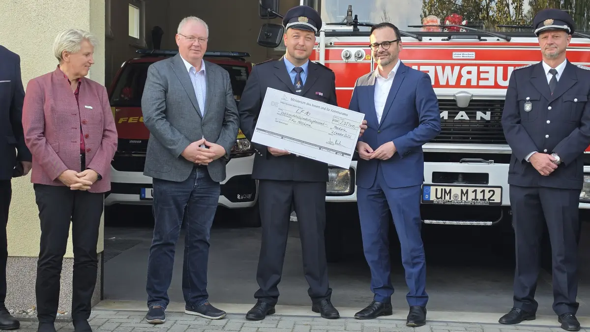 Ortswehrführer Philipp Schön nimmt von Brandenburgs Innenminister Dr. Jan Redmann den Fördermittelscheck über 275.000 Euro für die Beschaffung eines Feuerwehrfahrzeuges LF 10 entgegen.