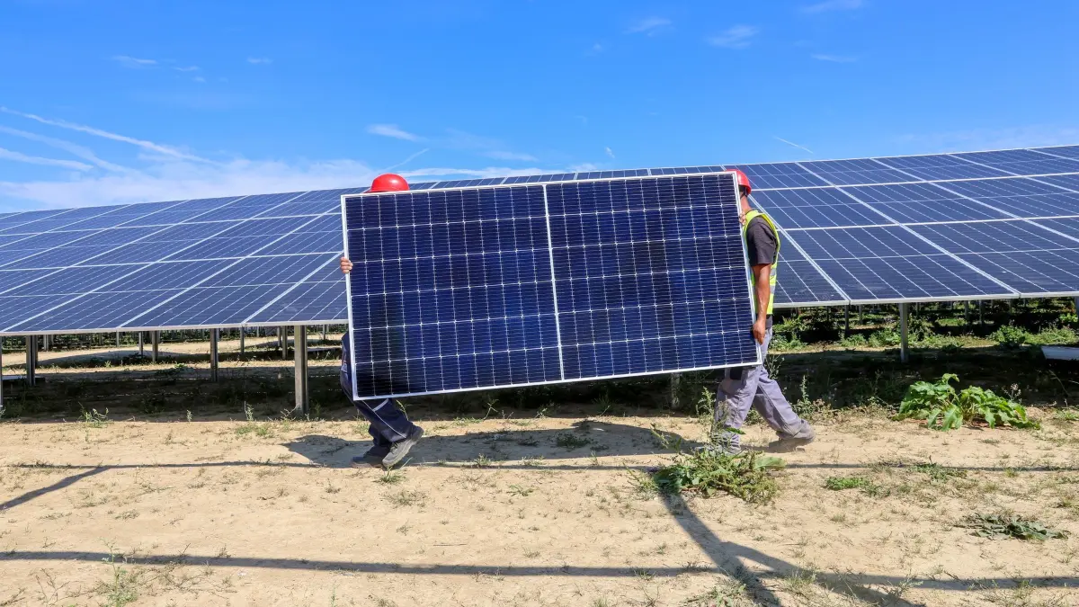 Klimaschutz in Baden-Württemberg: Mitarbeiter einer Montagefirma tragen ein Solarmodul durch den Solarpark in Langenenslingen. (zu dpa: «Klimaexperten stellen dem Land Zeugnis aus - das letzte Mal?»)