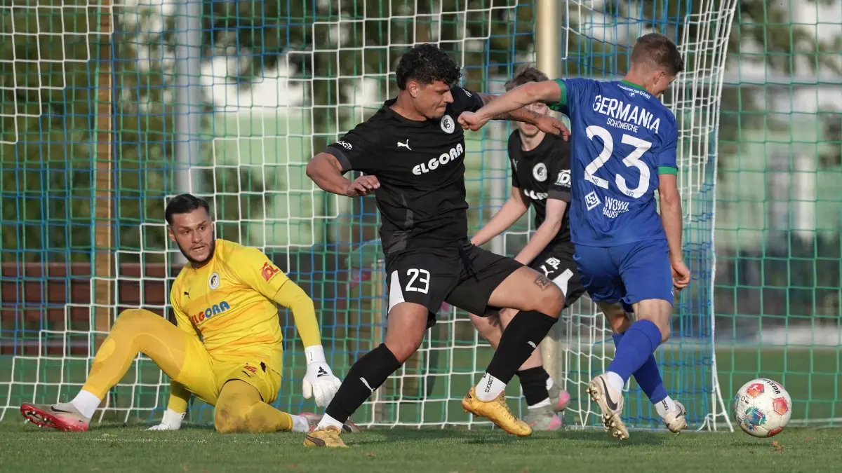Fussball : Schöneiche, Fussball Brandenburgliga, Germania Schöneiche - TuS Sachsenhausen, Keeper Mateusz Zlotogorski schon am Boden während Marc Moldenhauer noch bei Moritz Borchardt ist
FOTO BENK 10.10.2026