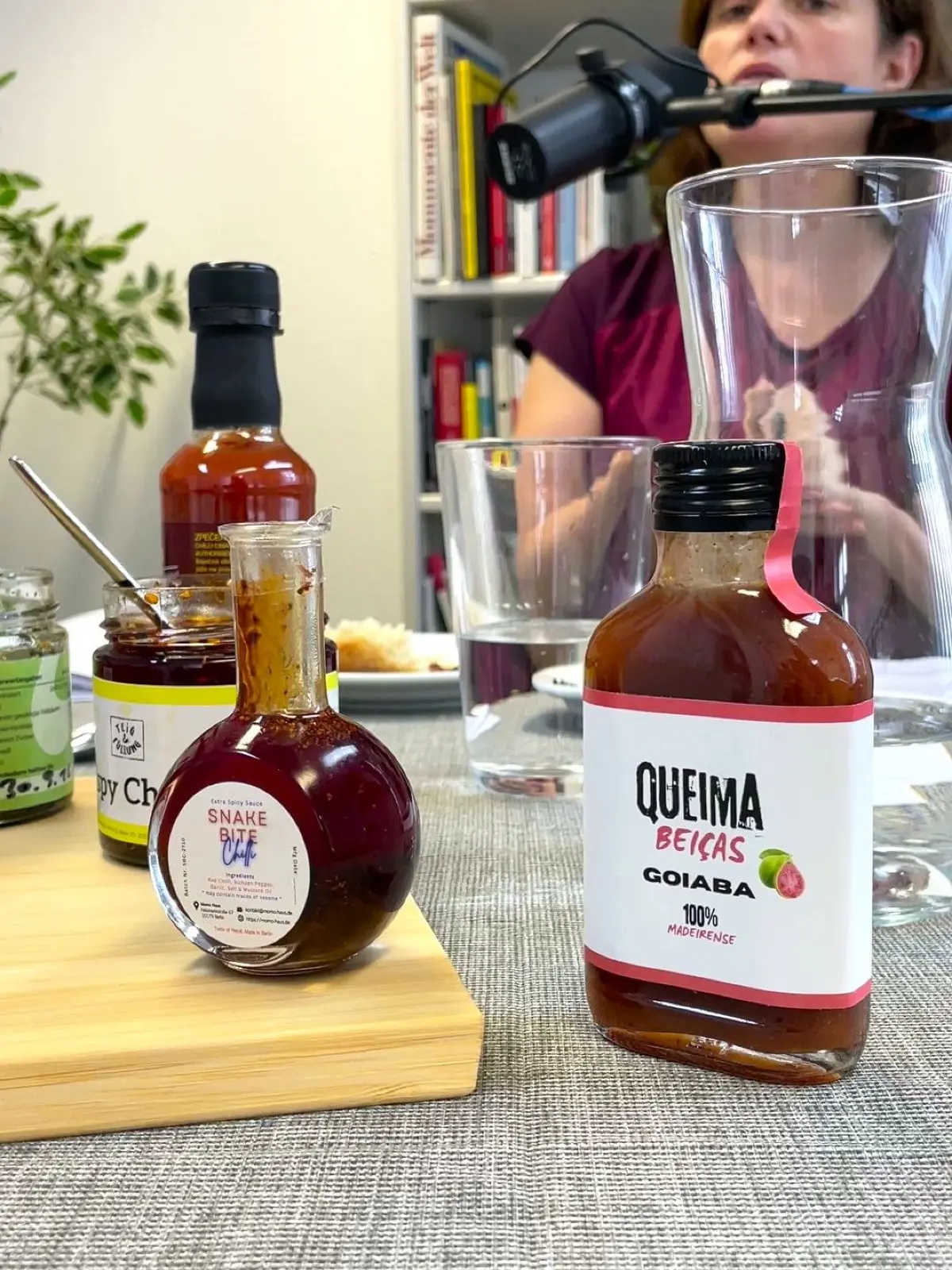 Während einer Aufnahme des Podcasts "Brandenburg, lass uns über Essen reden" zu Chilisaucen kleiner Hersteller, online gegangen am 15.10.2026. Im Vordergrund Produkte im Test, im Hintergrund Sandra Ketterer