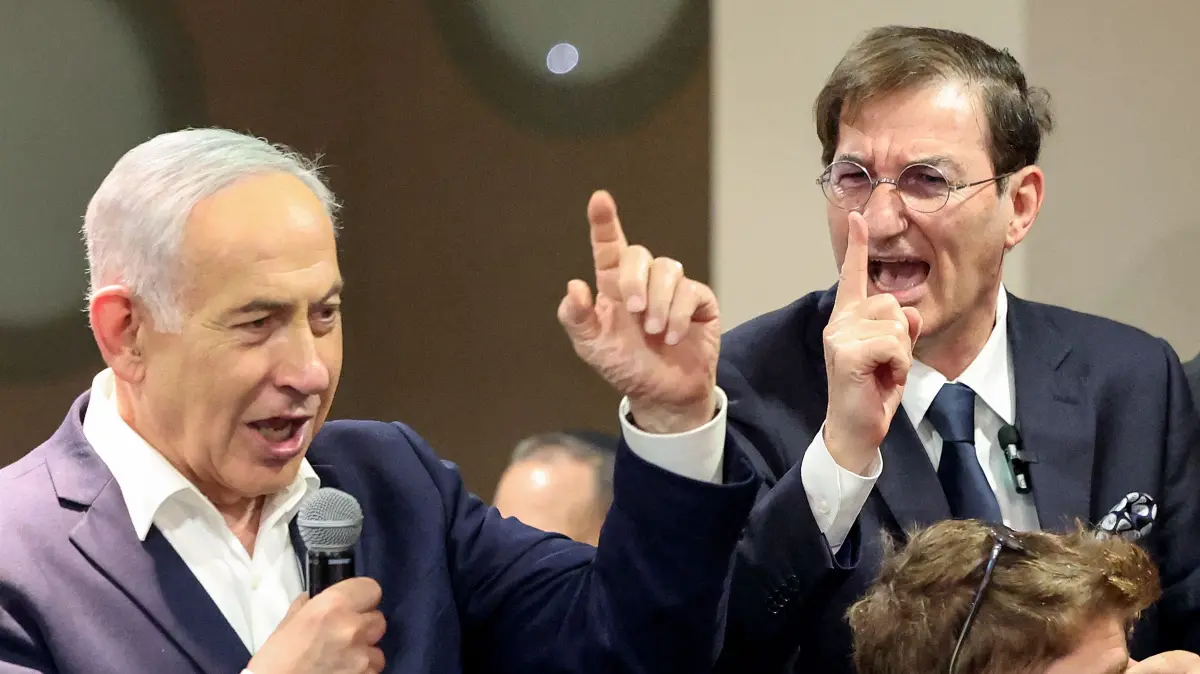 ISRAEL-POLITICS-ELECTION: Israel's Prime Minister Benjamin Netanyahu (L) speaks to his supporters as Boaz Bismuth, chairman of the Foreign Affairs and Defence Committee in the Knesset, reacts during a Likud Party meet-and-greet held as part of the campaign ahead of Israel's legislative election, at King Solomon Hotel in Netanya on October 22, 2026. Israel heads to the polls on October 27 in its first election since the October 7, 2023 Hamas-led attack, in what is seen as a referendum on the prime minister. (Photo by JACK GUEZ / AFP)